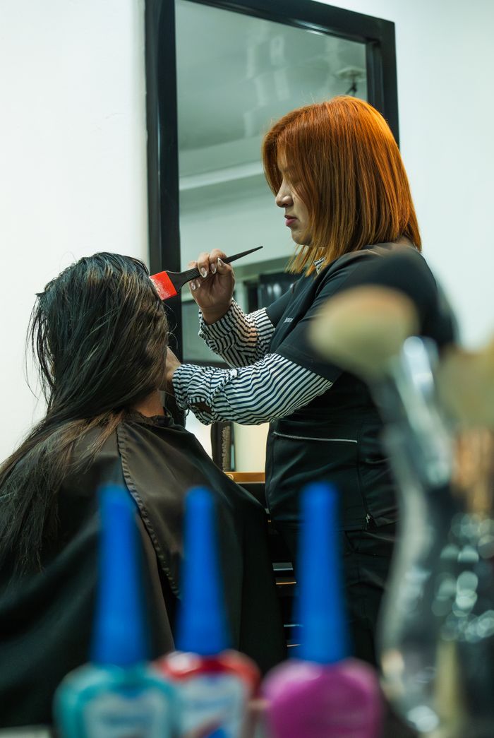 A stylist applies hair color to a client in a modern salon setting.