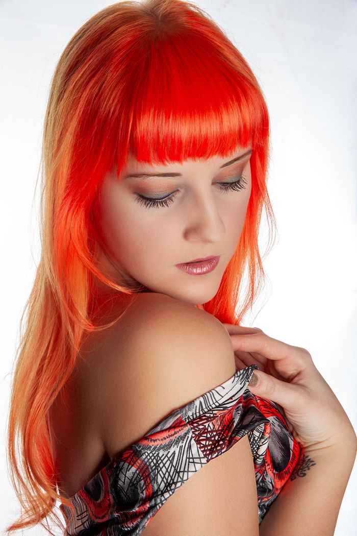 Beautiful woman with striking red hair posing in an elegant off-shoulder outfit.