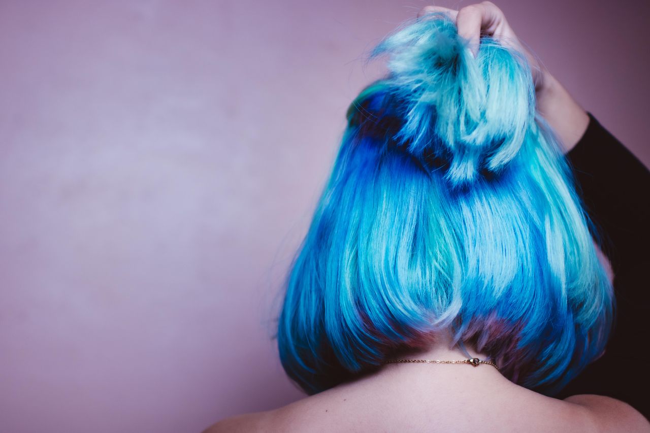A striking image showcasing vibrant blue hair styled in an elegant updo against a soft backdrop.