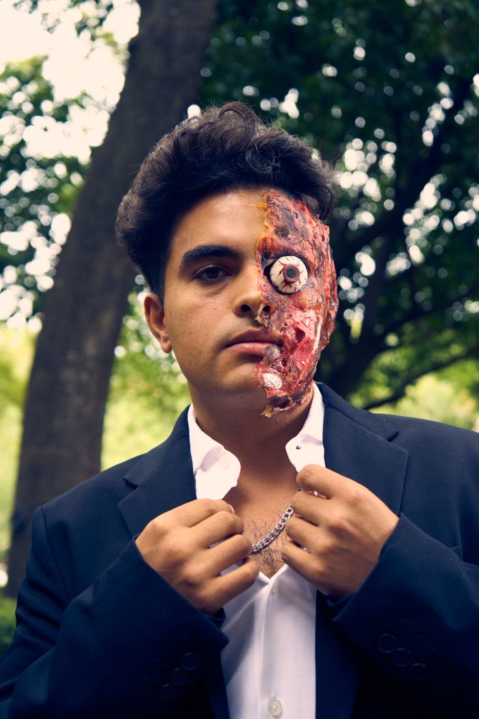 Portrait of a horror character with distressed face makeup in a forest setting.
